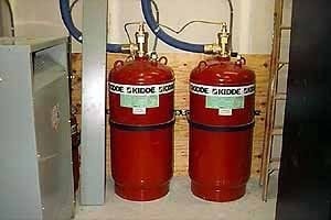 Two red Kidde fire-suppression cylinders with blue discharge hoses