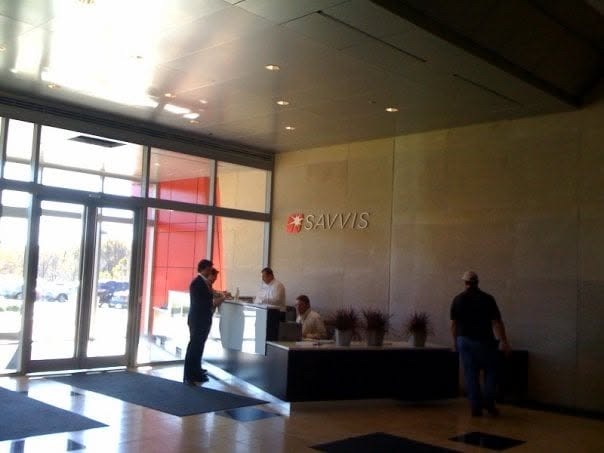 Savvis lobby and reception desk with large SAVVIS wall letters and red square starburst logo beside glass entrance doors